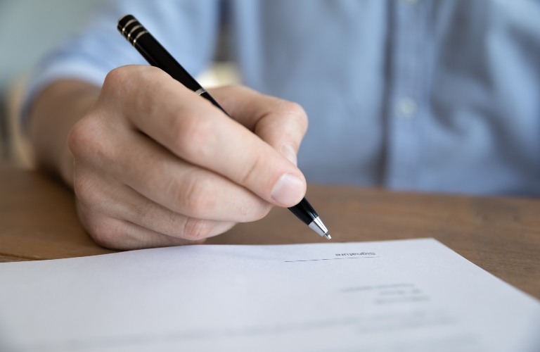 Close up male hand holding pen signing life or health insurance