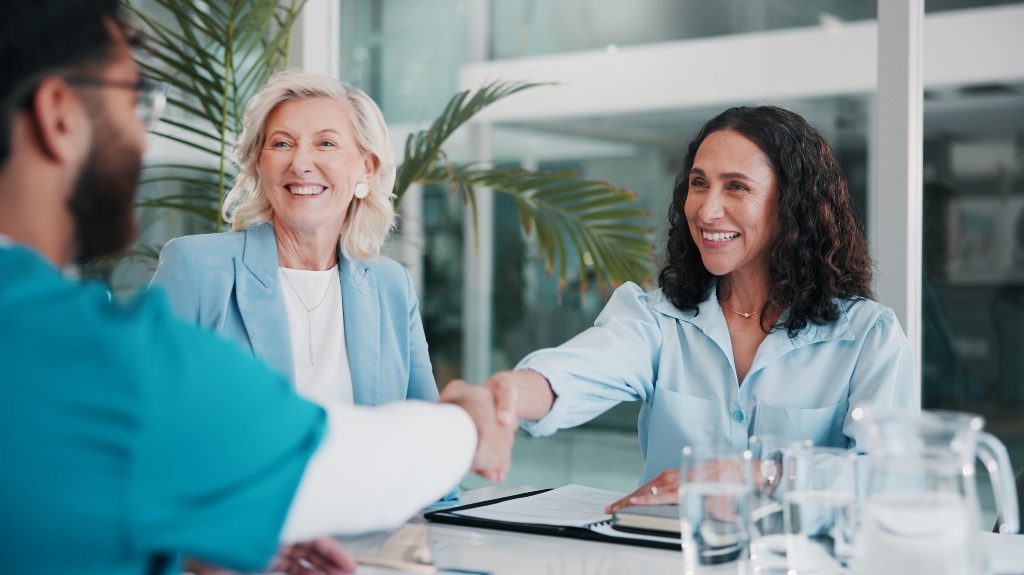 Nurse, people and handshake in meeting for healthcare agreement